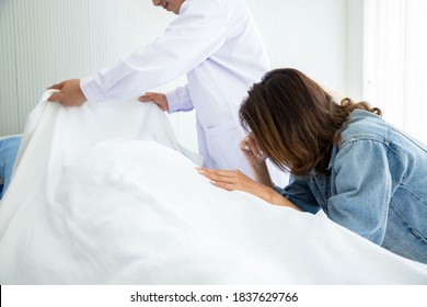 Beautiful woman sat down and regretted her father's death from a hospital illness. The doctor put a white cloth over the body of the deceased. Sad and cry concept