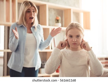 Beautiful woman is scolding her teenage daughter, girl is covering ears and ignoring her mom