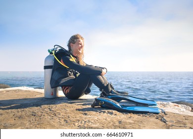 Beautiful Woman With Scuba Diver Equipment, Looking The Horizon From A Pier