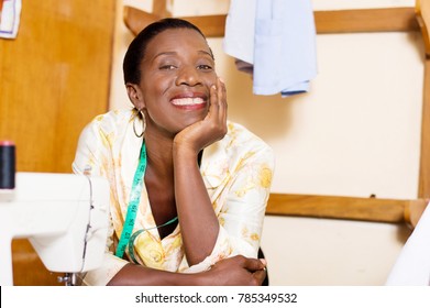 Beautiful woman seamstress smiling leaning on the table of her sewing machine
and hand under the chin
