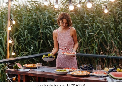 Beautiful woman setting up the table for outdoor dinner party. - Shutterstock ID 1179149338