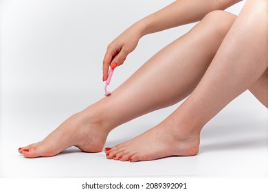 beautiful woman shaves her legs on a white background. isolated