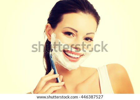 Beautiful woman shaving her face with a razor