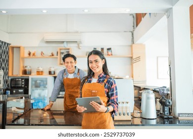 beautiful woman shop owner wearing apron smiling holding a tablet at coffee shop