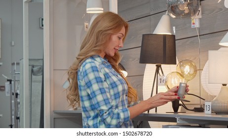 Beautiful woman shopping for lighting for her apartment at furniture store