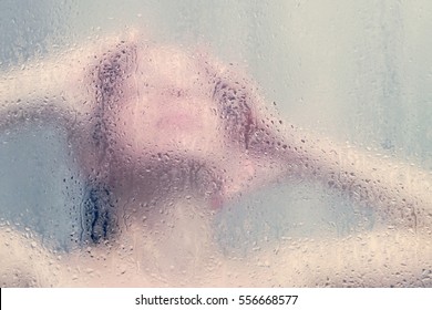 Beautiful Woman In The Shower Behind Glass With Drops