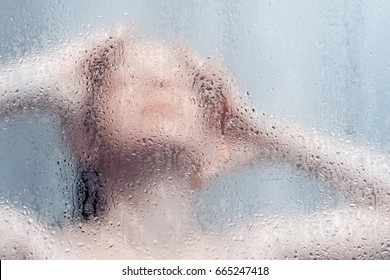 Beautiful Woman In The Shower Behind Glass With Drops