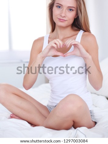 Beautiful woman showing heart shape on her hand , sitting bed. Beautiful woman