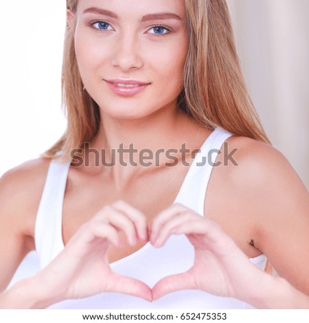 Beautiful woman showing heart shape on her hand , sitting bed