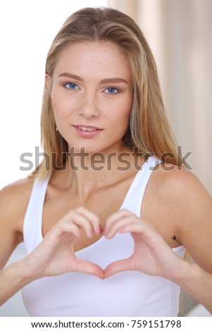 Beautiful woman showing heart shape on her hand , sitting bed. Beautiful woman