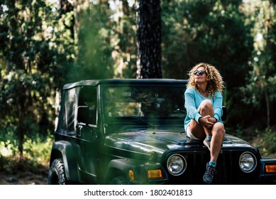 Beautiful Woman Sit Down On The Off Road Car And Enjoy The Nature Around - Concept Of Off Grid Vacation And Trip With Wood And Trees - People Enjoy The Outdoor Leisure Activity With Vehicle