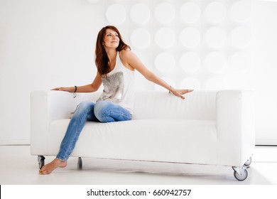 Beautiful woman siting on the white couch in the white room - sm