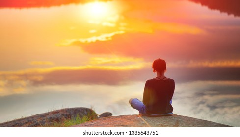 Beautiful woman sits in a pose of a  lotus on high place with amazing view of the lake sunset practice yoga meditation Kundalini energy mindset intuition prana. Solitude harmony mental freedom concept - Powered by Shutterstock