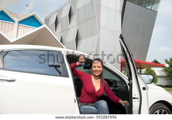 Beautiful\
woman sitting in the car with key in\
hand.