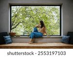 Beautiful woman sitting in front of large window, clean space.