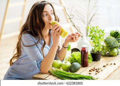 Beautiful Woman Sitting With Healthy Green Food And Drinking Smoothie At Home. Vegan Meal And Detox Concept