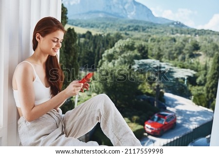 beautiful woman sitting on the balcony with phone beautiful mountain view summer Perfect sunny morning