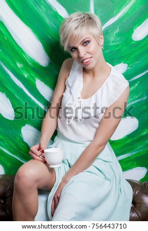 Beautiful woman sitting on leather sofa. Coffeebreak in loft interior.