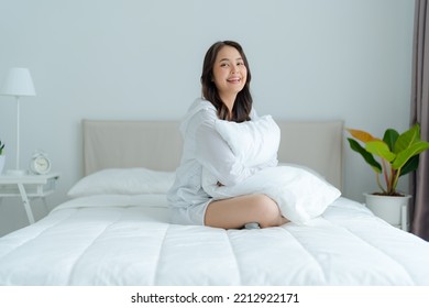 A beautiful woman sitting on a pillow in her bedroom, smiling, laughing happily. with a bright face - Powered by Shutterstock