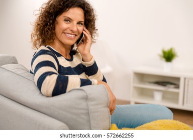 Beautiful Woman Sitting On The Sofa And Making A Phone Call