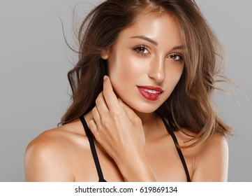 Beautiful Woman Skin Tanned Red Lips Healthy Beauty Skin Smile. Spa Beautiful Model Girl Cute Face over gray background.