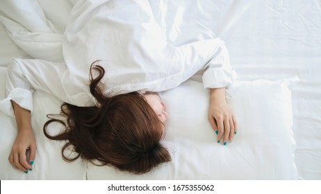 Beautiful Woman Sleeping In The Bedroom. Lady Lying Face Down On The Bed. Relaxing The Morning At White Room In The Morning.Warm Tone.

