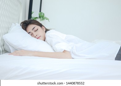 Beautiful Woman Sleeping In The Bedroom.
Woman Lying Face Down On The Bed.Girl Wearing A Pajama Sleep On A Bed In A White Room In The Morning.Warm Tone.