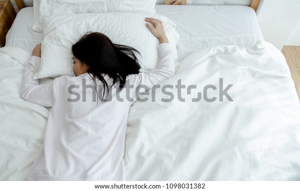 Beautiful woman sleeping\
in the bedroom.\
Woman lying face down on the bed.He slept with\
sleep.A woman wearing a pajama sleep sleeping on a bed in a white\
room in the morning.