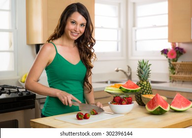 Beautiful woman slicing strawberries in kitchen on cutting board wood bright home smile perfect hair teeth - Powered by Shutterstock