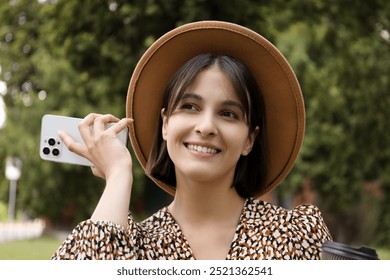 Beautiful woman with smartphone listening to voice message outdoors - Powered by Shutterstock