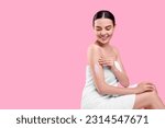 Beautiful woman with smear of body cream on her arm against pink background, space for text