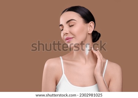 Beautiful woman with smear of body cream on her neck against light brown background. Space for text