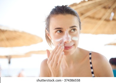 Beautiful Woman Smears Face Sunscreen At The Beach For Protection.