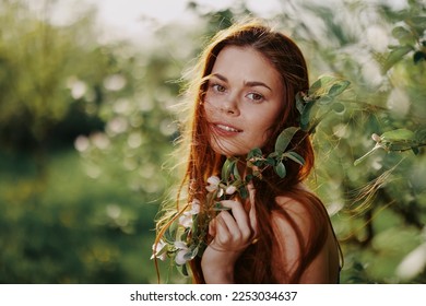 Beautiful woman smile close-up face with long red hair flying hair near the tree in the summer sun in the nature in the park smiling without allergies in a blue dress, the concept of health and beauty - Powered by Shutterstock