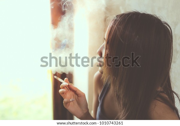 美しい女性がたばこを吸っている 魅力的な美しい女の子はタバコやタバコの煙が少しも吸えない綺麗な女の子がタバコの煙を吹いている 彼女は自分の将来の人生を考え ストレスを感じ コピー空間を感じている の写真素材 今すぐ編集