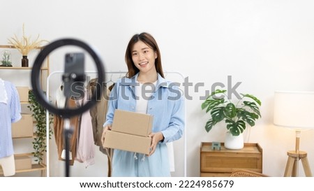 Beautiful woman with a social media influence is greeting the audience for recording vlog video live streaming, Lift the postage box during the live show to confirm the customer's order.
