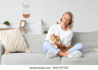 Mujer hermosa en zapatillas suaves con el gato lindo que se sienta en el sofá en casa