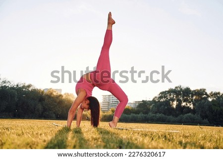 Beautiful woman in sportive clothes doing fitness exercises outdoors on the field.