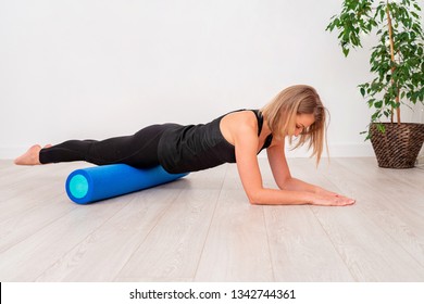 Beautiful woman in sportswear, Pilates instructor stretching and warming up with foam roller. The plank exercise with emphasis on the roll fitness. with free text space.