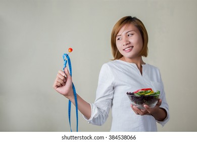 Beautiful Woman Standing Holding Bowl Of Salad Looking At Fork Dipping Tomato And Have Measure Tape Roll On The Fork She Smiley To Fork