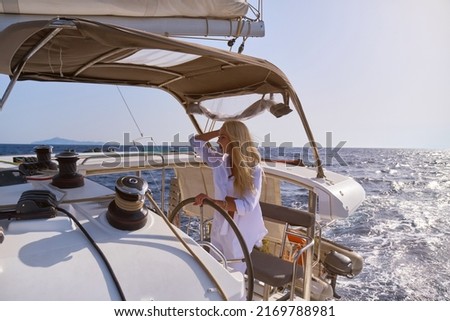 beautiful woman standing on yacht captain's bridge at sunny summer day
