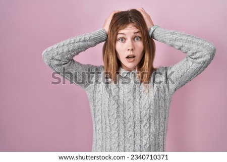 Beautiful woman standing over pink background crazy and scared with hands on head, afraid and surprised of shock with open mouth 