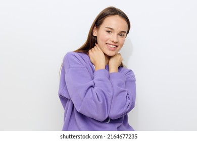 a beautiful woman stands on a white background in a purple tracksuit joyfully presses her hands to her neck, slightly hunched over