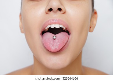 Beautiful woman sticking out her tongue and showing her young piercing
