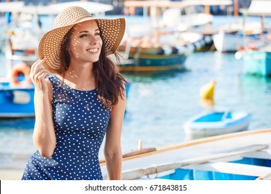 Beautiful woman in straw hat sitting on boat at the beach. Summer style.