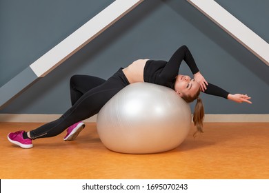 Beautiful Woman Stretched Arms And Legs In Different Directions Lying On A Fitness Ball In The Gym