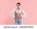 Beautiful woman in stylish corset posing on pink background