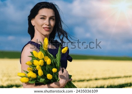 Beautiful Woman in summer dres standing in colorful tulip flower fields in Amsterdam region, Holland, Netherlands. Magical Netherlands landscape with tulip field in Holland Trevel and spring concept.