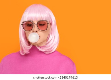 Beautiful woman in sunglasses blowing bubble gum on orange background, space for text - Powered by Shutterstock