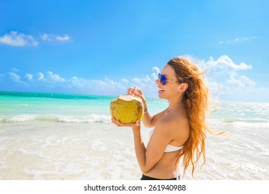 Beautiful woman with sunglasses on a tropical beach enjoying ocean sea view, taking deep breath 